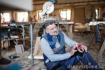 Man with an injured hand after accident at work in the carpentry workshop. Stock Photo