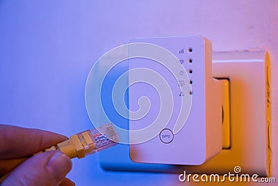 Man insert ethernet cable into WiFi extender device which is in Editorial Stock Photo