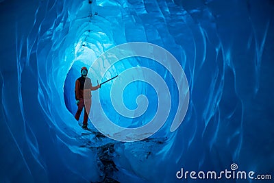 Man inside a melting glacier ice cave. Cut by water from the melting glacier, the cave runs deep into the ice of the Matanuska Stock Photo