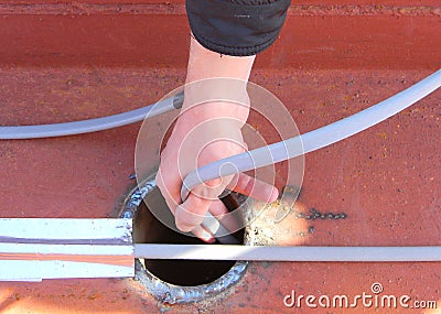 A man is installing gutter deicing, ice-melting, self regulating heating cablesâ€Ž in an industrial rain gutter system Stock Photo