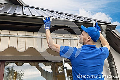 Man installing house roof gutter system Stock Photo