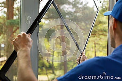 Man installing mosquito net wire mesh on house window Stock Photo