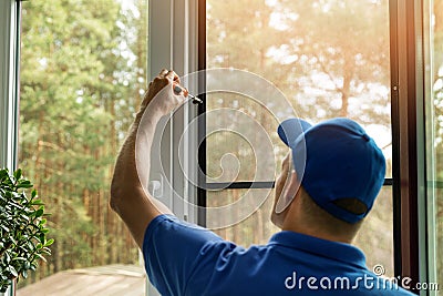 Man installing mosquito net wire screen on house window Stock Photo