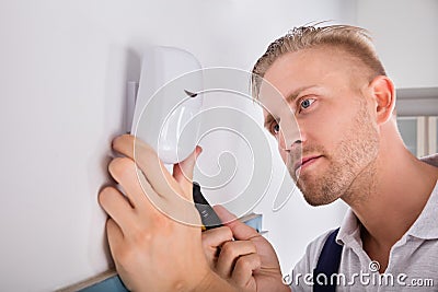 Man Installing Motion Detector For Security System Stock Photo