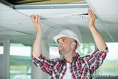 Man installing suspended ceiling in house Stock Photo