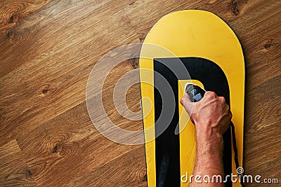 Man ironed wax on a snowboard, lying wooden floor Stock Photo