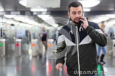 Man in jacket with a mobile phone near turnstile in subway Stock Photo