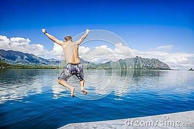 Man jumping into the ocean while on a beautiful scenic Hawaiian vacation Stock Photo