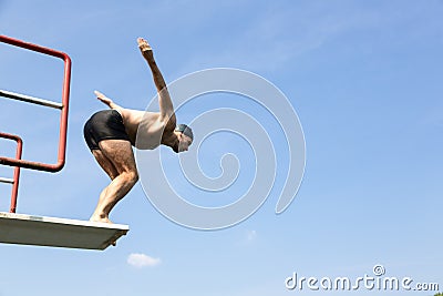 Man jumping off diving board at swimming pool Stock Photo