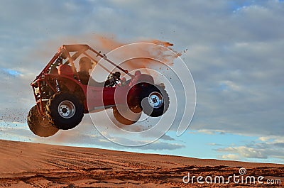 Man Jumping Quad Through the Air on Sand Dune Stock Photo