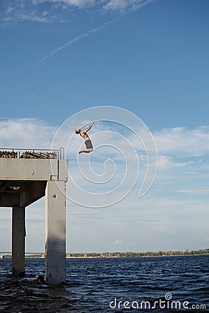 Man jumping into sea from pier Stock Photo