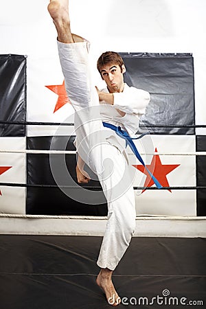 Man, karate and high kick for martial arts in ring, self defense or jiujitsu training for fighting match. Male person Stock Photo
