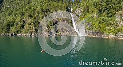 Man in kayak paddling towards the waterfall Stock Photo