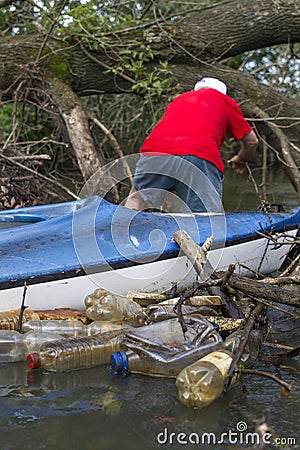 A Man In A Kayak In A River Full Of Trash Stock Photo