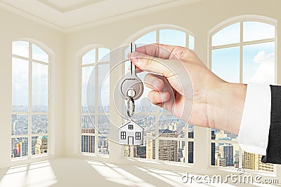 Man with key in hand in modern sunny white room with city view Stock Photo