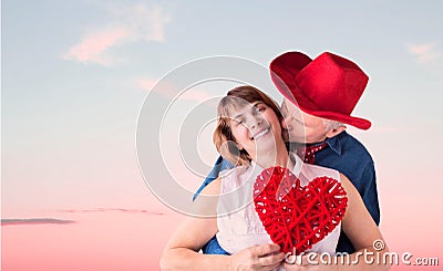 Man kissing his wife while she holds a valentine. Stock Photo