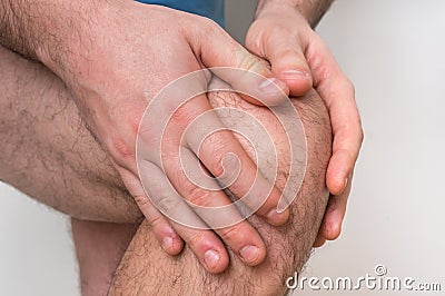 Man with knee pain is holding his aching leg Stock Photo