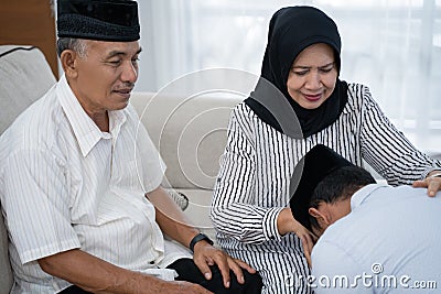 Man kneeling and kiss his parent`s hand asking for forgivness Stock Photo