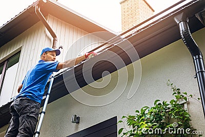 Man on ladder cleaning house gutter Stock Photo