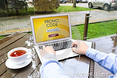 Man with laptop activating promo code at wooden table outdoors, closeup Stock Photo