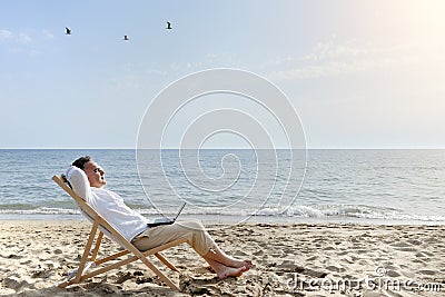 Man with laptop computer relaxing on the beach Stock Photo