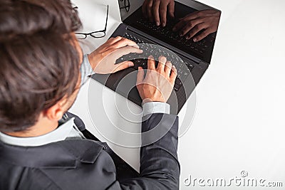 Man with laptop typing on the keyboard. On white table.. Stock Photo