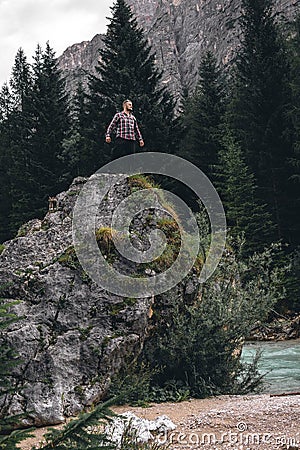 Man on a large stone, a boulder, among the incredibly beautiful river of turquoise color, vertical photo. Dolomites mountains, Stock Photo