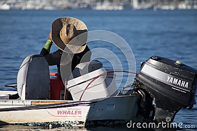 Man in a large straw hat sits in his Boston Whaler boat at the e Editorial Stock Photo