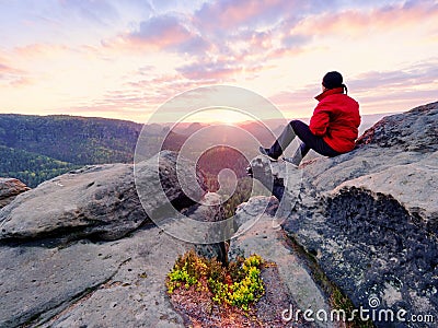 . Man lay on summit, bellow autumn valley. Bright morning Sun shining in sky. Stock Photo