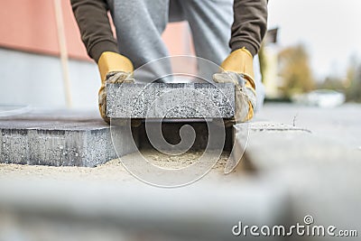 Man laying a paving brick placing it on the sand foundation Stock Photo