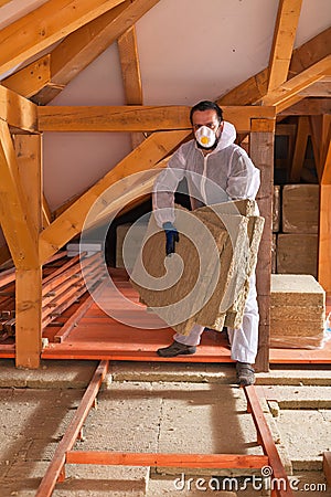 Man laying thermal insulation layer under the roof Stock Photo
