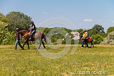 Man leading a horse with young woman and her child ride Editorial Stock Photo