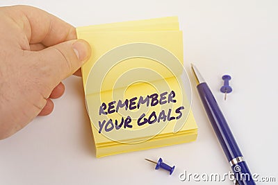 The man is leafing through the stickers, the sheet says - REMEMBER YOUR GOALS Stock Photo