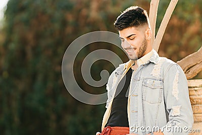 Man leaning against a column in a park smiling with a blank stare Stock Photo