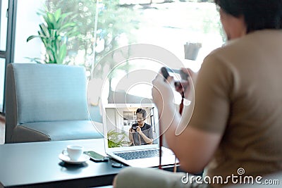 Asian male watching online training workshops for camera function by notebook in the living room Stock Photo