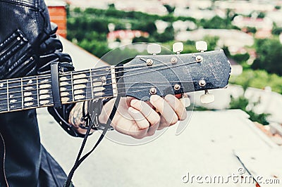 Man in a leather jacket close up tunes old black acoustic guitar Stock Photo