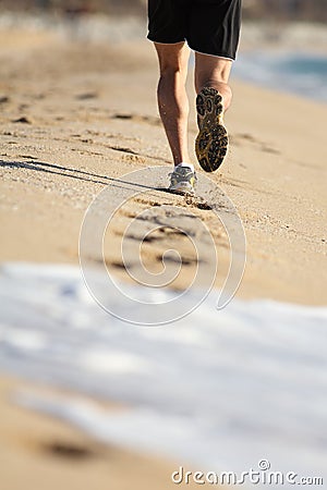 Man legs running on the sand of a beach Stock Photo