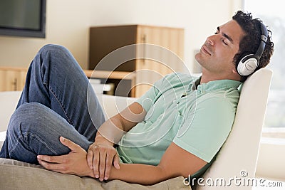 Man in living room listening to headphones Stock Photo