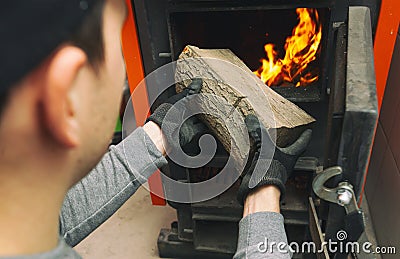 Man loads the firewood in the solid fuel boiler in the boiler room. Stock Photo