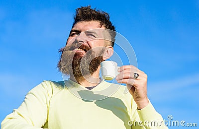 Man with long beard enjoy coffee. Man with beard and mustache on smiling face drinks coffee, blue sky background Stock Photo