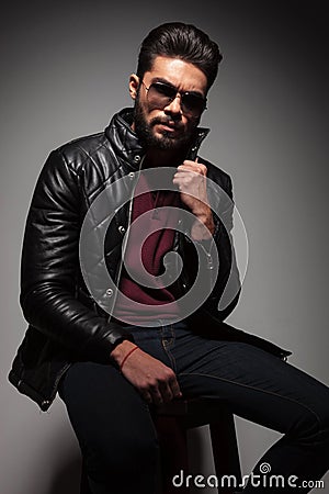 Man with long beard is pulling his leather jacket's collar Stock Photo