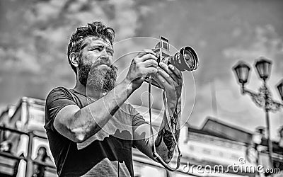 Man with long beard shooting photos. Manual settings. Photographer hold vintage camera. Modern blogger. Content creator Stock Photo