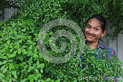 A man with a Long hair and a mustache peeking out from the bushes of Terminalia ivorensis Chev bedew Stock Photo