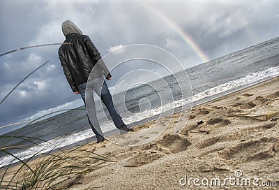 Man looking at the sea and rainbow Stock Photo