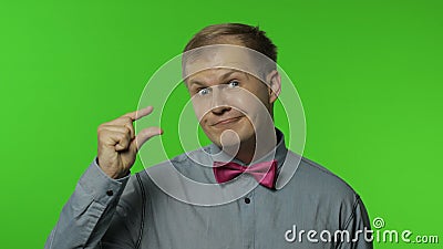 Man looking at camera showing a little bit gesture, feeling sceptical about small size, low scale Stock Photo