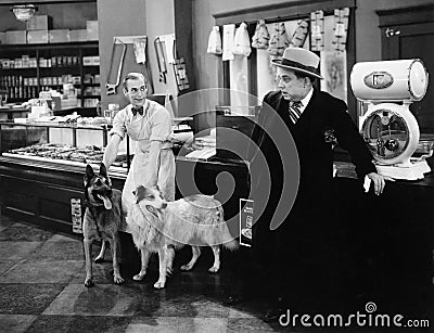 Man looking fearful at two dogs in a butcher store Stock Photo