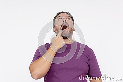 A man looking highly puzzled and perplex while looking up in disbelief, sticking his finger and stretching his mouth. Isolated on Stock Photo