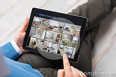 Man looking at home security cameras on tablet computer Stock Photo