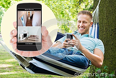 Man Looking At Home Security System On Mobilephone Stock Photo