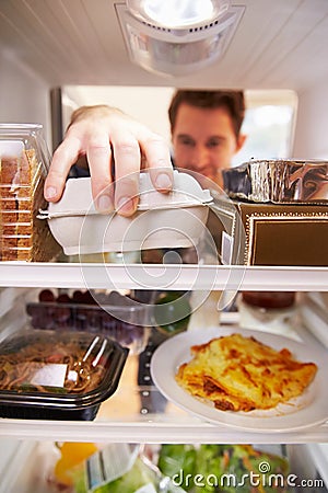 Man Looking Inside Fridge Filled With Food And Choosing Eggs Stock Photo